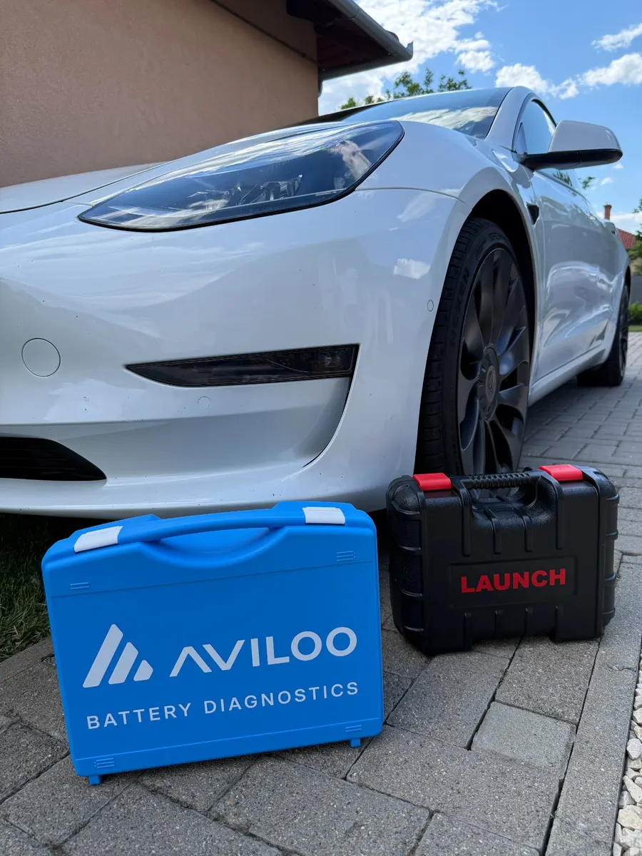 AVILOO akkumulátor-diagnosztikai koffer egy fehér Tesla előtt