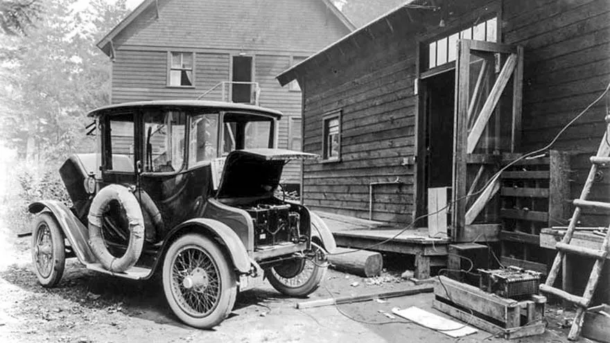 Korai elektromos autó töltése egy ház udvarán az 1910-es években